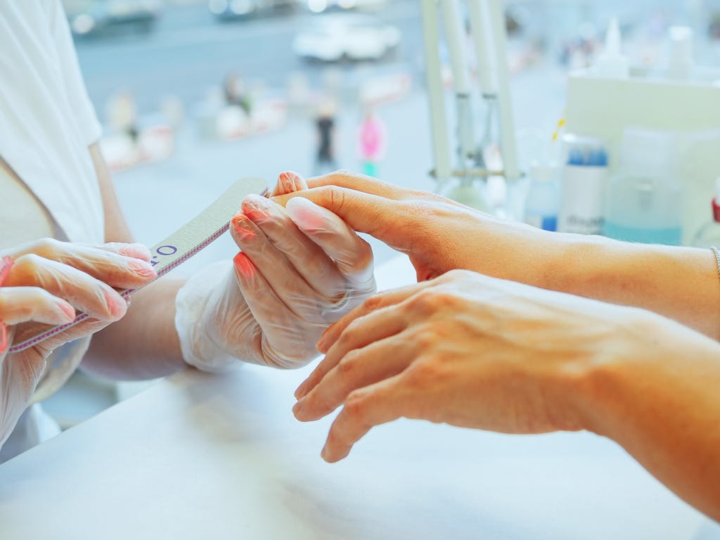 Close-up of a manicurist performing a nail file treatment on a customer's hand in a salon. bağlıca manikür pedikür